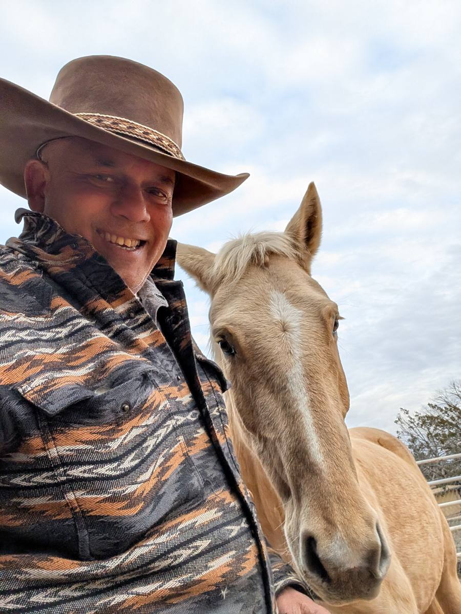 Paul D'Souza in a cowboy hat beside one of his palomino Navajo Mustangs at Casa D'Souza Ranch