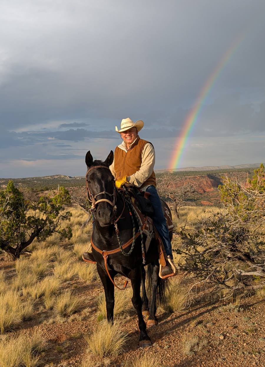 Paul D'Souza riding one of his Navajo Mustangs beneath a rainbow in the high desert at Casa D'Souza Ranch